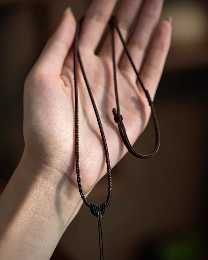 Braided cord necklaces with knotted loops held in an open hand